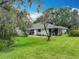 Charming backyard featuring a well-maintained lawn, mature trees, and a cozy patio area connected to the home at 42 Grenewood Ln, Haines City, FL 33844
