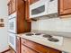 A close up of the cooktop and oven with wooden cabinetry and white tile backsplash in the kitchen area at 42 Grenewood Ln, Haines City, FL 33844