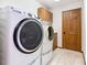 Laundry room featuring modern white washer and dryer units and wood cabinets at 42 Grenewood Ln, Haines City, FL 33844