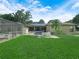 Expansive backyard with a well-maintained lawn, screened-in patio, and solar panels on the roof at 4333 Shadow Wood Way, Winter Haven, FL 33880