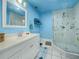 A blue bathroom with a glass shower and a mirror over the sink at 4333 Shadow Wood Way, Winter Haven, FL 33880