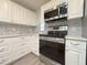 Updated kitchen with white cabinets, stainless steel appliances, and gray backsplash for a sleek look at 4480 Turnberry Ln, Lake Wales, FL 33859
