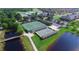 Aerial view of tennis courts with a green surface, situated near a lake, a golf course, and residential buildings at 4480 Turnberry Ln, Lake Wales, FL 33859