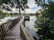 Private wooden dock on the lake featuring lush surroundings and a boat in the background at 502 Little Lake Ct, Winter Haven, FL 33884