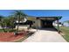 A manufactured home with a covered carport, palm trees in the yard, and a paved driveway at 6562 Chinaberry Ne Dr, Winter Haven, FL 33881