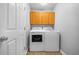 Bright laundry room featuring wood-look floors, upper cabinets and a new washer and dryer at 7120 Summit Dr, Winter Haven, FL 33884