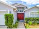 Close up of a front entrance featuring a red double-door, manicured landscaping, and an arched transom window at 799 Highland Crest Loop, Lake Wales, FL 33853