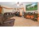 Cozy living room featuring tile flooring, a ceiling fan, a leather sofa, and a mounted television at 808 Ware Ne Ave, Winter Haven, FL 33881