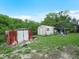Exterior shot of the property showcasing two storage sheds, with the backdrop featuring a serene, wooded area at 808 Ware Ne Ave, Winter Haven, FL 33881
