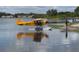 A yellow seaplane sits on the water, ready for flight on this waterfront property at 1010 Biltmore Nw Dr, Winter Haven, FL 33881