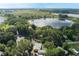 Stunning aerial view of a yellow home nestled by a picturesque lake surrounded by lush greenery and trees at 1163 Lake Dr, Lake Wales, FL 33859