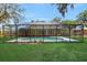 The screened in pool has a concrete surround with a lush lawn beyond at 1226 Lake Loop, Winter Haven, FL 33880