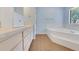 Bright bathroom with tub, white cabinets, and wood-look tile flooring at 1226 Lake Loop, Winter Haven, FL 33880