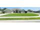 Well-manicured front yard of a single-story home featuring a lush green lawn, complemented by a paved driveway and sidewalk at 1400 Eagle Crest Blvd, Winter Haven, FL 33881