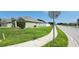 Spacious side yard featuring green grass, a sidewalk, and a glimpse of the home's exterior with a white fence at 1400 Eagle Crest Blvd, Winter Haven, FL 33881