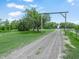 A scenic view of a lengthy gravel driveway leading to a tranquil property, embraced by lush greenery and towering trees at 1850 S Lake Reedy Blvd, Frostproof, FL 33843