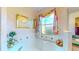 Relaxing bathtub with window, decorative accents, and floral curtains at 1902 Southern Dunes Blvd, Haines City, FL 33844