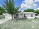Charming single-story home with a well-manicured lawn, mature tree, and solar panels on the roof at 2100 Magnolia Ave, Haines City, FL 33844
