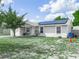 Inviting exterior view of a single-story home featuring solar panels, lush lawn, and a charming front entrance at 2100 Magnolia Ave, Haines City, FL 33844