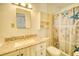 This bathroom features a granite countertop, a large mirror, and a shower-tub combo with a beachy curtain at 230 W Harbord St, Lake Alfred, FL 33850