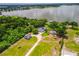 Aerial view of a lakeside house featuring a detached garage with circular drive and mature trees at 250 Brigham Nw Rd, Winter Haven, FL 33881