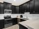 Modern kitchen featuring black cabinets, white quartz countertops, and stainless appliances at 2824 Attwater Loop, Winter Haven, FL 33884