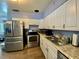 The kitchen has stainless steel appliances, wood-look flooring, and white cabinets for storage at 3022 Hickory Nw St, Winter Haven, FL 33881