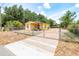 View of a yellow house with a fenced front yard, a driveway, and lots of trees at 305 Armour Ave, Auburndale, FL 33823