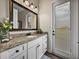 Bright bathroom with a granite countertop, modern vanity, decorative mirror, and an exterior glass door at 3805 Mammoth Grove Rd, Lake Wales, FL 33898