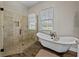 Bright bathroom features a glass shower and clawfoot tub with wood-look flooring and window at 3805 Mammoth Grove Rd, Lake Wales, FL 33898
