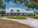 Charming single-story home features a metal roof, lovely front porch, circular driveway, and beautifully manicured landscaping at 3805 Mammoth Grove Rd, Lake Wales, FL 33898