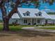Inviting one-story home with metal roof, dormer windows, front porch and circular driveway, shaded by mature trees at 3805 Mammoth Grove Rd, Lake Wales, FL 33898