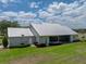 Back exterior view of house featuring a well manicured lawn, a metal roof, and partial view of the back patio at 3805 Mammoth Grove Rd, Lake Wales, FL 33898