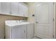 Efficient laundry room with white cabinets and appliances next to a door at 3844 Bedford Ave, Winter Haven, FL 33884