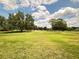 Expansive lush, green front yard with mature trees, and a road running past the home at 426 Gleneagles Ct, Winter Haven, FL 33884