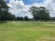 Expansive lush, green front yard with mature trees, and a road running past the home at 426 Gleneagles Ct, Winter Haven, FL 33884