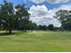 Expansive lush, green front yard with mature trees, and a road running past the home at 426 Gleneagles Ct, Winter Haven, FL 33884