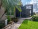 Backyard featuring a screened lanai, manicured lawn, and mature palm trees at 4327 Gullane Dr, Lake Wales, FL 33859
