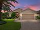 Beautiful home exterior with lush landscaping, brick driveway, and a two-car garage at sunset at 4327 Gullane Dr, Lake Wales, FL 33859