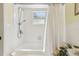 All-white bathroom with tub and shower, complemented by a window for natural light and a clean aesthetic at 441 San Jose Dr, Winter Haven, FL 33884