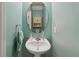 A clean, bright bathroom with a pedestal sink and round mirror complements the light blue walls at 476 Haines Trl, Winter Haven, FL 33881