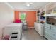 Cozy bedroom with built-in shelving, orange accent wall, and bright window at 476 Haines Trl, Winter Haven, FL 33881