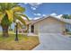 Beige single-story home with a well-manicured lawn and a two-car garage at 492 Sweetwater Way, Haines City, FL 33844