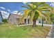 Charming home exterior featuring a well-manicured lawn, mature palm tree, and cozy patio with outdoor seating at 492 Sweetwater Way, Haines City, FL 33844