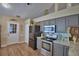 Cozy kitchen features stainless steel appliances, grey cabinets, granite countertops and wood flooring at 492 Sweetwater Way, Haines City, FL 33844