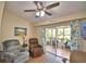 Relaxing living area with two recliners, ceiling fan, and sliding doors leading to the screened lanai at 492 Sweetwater Way, Haines City, FL 33844