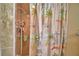 Walk-in shower with patterned curtain featuring palm trees, cars, and beach shacks at 492 Sweetwater Way, Haines City, FL 33844
