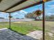 View of the home's expansive backyard with a covered back patio, hanging flower baskets, and a well-maintained fence at 541 Hatchwood Dr, Haines City, FL 33844