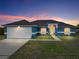Charming blue single-story home featuring a well-manicured lawn and a bright yellow front door at dusk at 541 Hatchwood Dr, Haines City, FL 33844