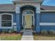Close up of a yellow front door with white trim, seasonal decor, and tidy landscaping at 541 Hatchwood Dr, Haines City, FL 33844